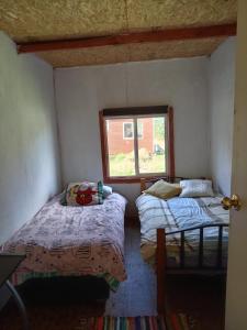 two beds in a small room with a window at Cabaña carmen velasquez in Calbuco
