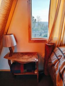 CABAÑA RAIZ INDOMITA PINTO Ñuble : غرفة نوم مع طاولة مع مصباح ونافذة +24 صورة