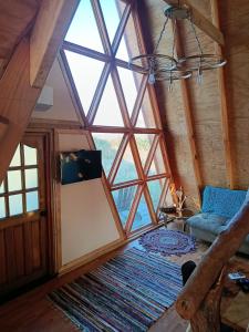 CABAÑA RAIZ INDOMITA PINTO Ñuble : غرفة في العلية مع نافذة كبيرة وأريكة