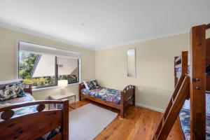 a bedroom with a bunk bed and a couch at Beachfront Unit - Belle Escapes Jervis Bay in Vincentia