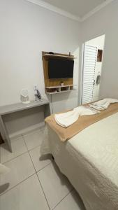 a bedroom with a bed and a desk and a television at Pousada Atalaia in Cuiabá
