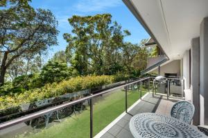 a balcony with tables and chairs and a view of a garden at Beachfront Unit - Belle Escapes Jervis Bay in Vincentia