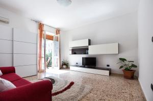 sala de estar con sofá rojo y TV en Seaside Holidays, en Alghero