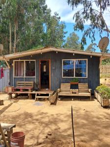 uma pequena casa com bancos em frente em Cabaña Entre eucaliptos em El Tabo
