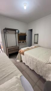 a bedroom with two beds and a television in it at Pousada Atalaia in Cuiabá