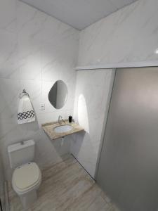 een witte badkamer met een toilet en een wastafel bij Loft em Florianópolis à 1km da praia in Florianópolis