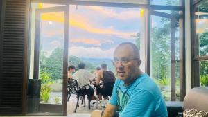 un hombre sentado en una mesa frente a una ventana en Pinnacle Life, en Matale