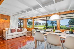 Hosts on the Coast Hahei Sands Villa B في هاهي: غرفة طعام مع طاولة وكراسي وأريكة