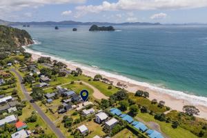 Hosts on the Coast Hahei Sands Villa B في هاهي: اطلالة جوية على شاطئ به بيوت ومحيط