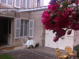 un patio con mesa y sillas frente a un edificio en La Maison Févret en Semur-en-Auxois