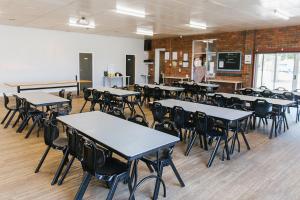 a classroom with tables and chairs and a woman in a room at Warra Gnan Coastal Camp in Warrnambool