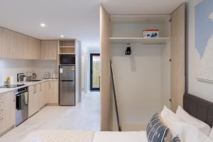 a small kitchen with a refrigerator and a counter at Modern Studio Near Stadium, Dining & City Fun in Christchurch