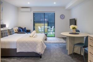 a bedroom with a bed and a desk and a table at Modern Studio Near Stadium, Dining & City Fun in Christchurch