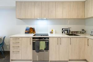 a kitchen with wooden cabinets and a stove top oven at Modern Studio Near Stadium, Dining & City Fun in Christchurch +13 photos