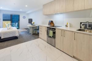 a kitchen with wooden cabinets and a bed in a room at Modern Studio Near Stadium, Dining & City Fun in Christchurch
