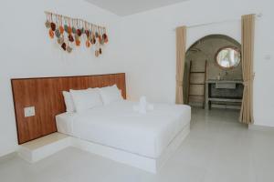 a bedroom with a large white bed and a table at MY BOO PRIVATE by DRAGONFLY in Nusa Penida