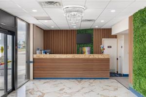 Baymont by Wyndham Richmond KY في ريتشموند: لوبي مكتب مع كاونتر الاستقبال والنباتات