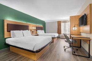 Baymont by Wyndham Richmond KY في ريتشموند: غرفة فندقية تحتوي على سريرين ومكتب وتلفزيون