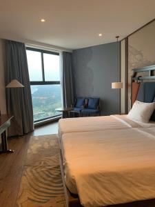 ein Hotelzimmer mit einem Bett und einem großen Fenster in der Unterkunft Minh Tân Apartment Mandala in Mui Ne
