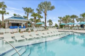 una piscina presso il resort con sedie bianche e palme di New 2025 Bambi Orlando Pool Vacation Home a Clermont