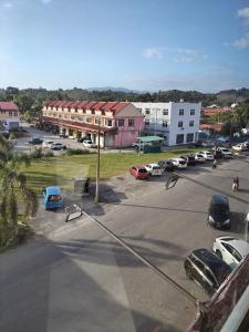 een parkeerplaats met auto's geparkeerd voor een gebouw bij T&S Management House in Gua Musang