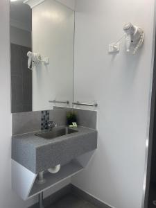 a bathroom with a sink and a mirror at Reef Gardens Motel in Proserpine +27 photos