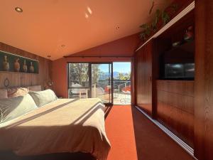 ワナカにあるPoolside Peaks - designer house, spa, fire, poolのベッドと大きな窓のある寝室