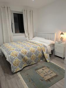 a bedroom with a bed with a comforter and a window at 2 bedroom house with yard in Cardiff