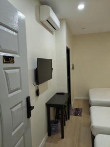 een kamer met een deur en een tafel en een tv bij T&S Management House in Gua Musang