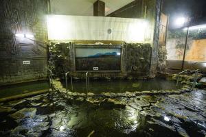 Una habitación con un televisor en una pared de piedra. en Ryokan Kintoki, en Aso 1 foto más