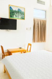 a bedroom with a bed and a table and a television at Tấn Đạt Hotel Quy Nhơn in Quy Nhon