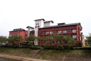 un edificio rojo y blanco con árboles delante de él en Ryokan Kintoki, en Aso