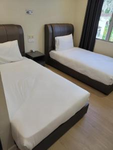 twee bedden in een hotelkamer met witte lakens bij T&S Management House in Gua Musang +24 foto's