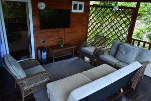 Un porche con un sofá y sillas y un televisor. en La Cabaña 0301, en Comayagua 12 fotos más