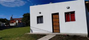 a white building with red doors on a yard at Sal y Arena in Colonia Chapadmalal
