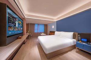 a bedroom with a large bed and a flat screen tv at Orange Hotel Beijing Xi'erqi in Beijing +29 photos
