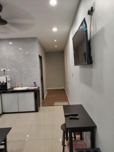 een keuken met een tafel en een tv aan de muur bij T&S Management House in Gua Musang