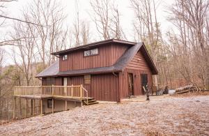a large red barn with a deck in the woods at The Bearfoot Cabin! Ideally located, decorated for Christmas, Fireplace, Game Room! in Sevierville