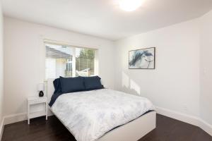 ein weißes Schlafzimmer mit einem Bett und einem Fenster in der Unterkunft The Langley Courtyard Home 2BR, 2BA for 6 Guests in Langley