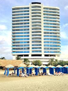 a group of beach umbrellas and a large building at Reserva del Mar Resort Club de Playa in Santa Marta