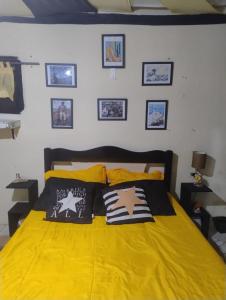 een slaapkamer met een geel bed met foto's aan de muur bij GNOME KIT HOUSE São Tomé das Letras- Mg in São Thomé das Letras