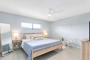 a bedroom with a bed and two tables and two windows at Chateau by the Sea 302 in Cocoa Beach