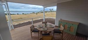 a porch with a table and chairs and a view of the ocean at Pelican Lagoon Retreat in Pelican Lagoon +24 photos