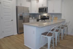 Townhome near beach and The Wharf Amphitheater! في شاطئ أورانج: مطبخ مع كونتر مع الكراسي وثلاجة