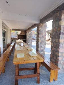 een lange houten tafel in een kamer met een stenen muur bij Cabañas Los Cardones Tilcara in Tilcara