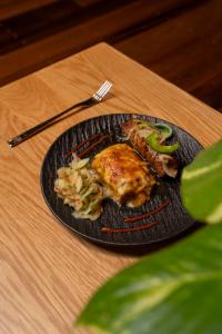 a black plate of food on a wooden table at Turtle Beach Hotel Calibishie in Woodford Hill