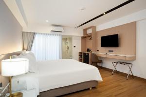 a hotel room with a white bed and a desk at P-Park Hotel Bangkok in Bangkok