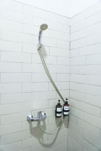 a shower with a hose attached to a white tiled wall at Rumah Canda in Bandung