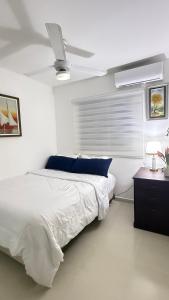 Apartamento en Santo Domingo Pablo mella morales في Hato Nuevo: غرفة نوم بيضاء مع سرير ومروحة سقف
