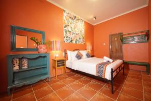 a bedroom with orange walls and a bed and a mirror at Amador by Suasana Villa in Jarakan +17 photos